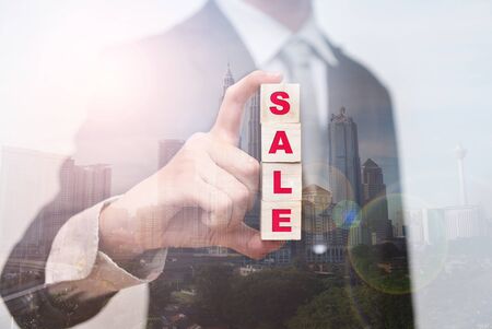 Double exposure of businessman show Sale words on wooden cube with city view as concept.の写真素材