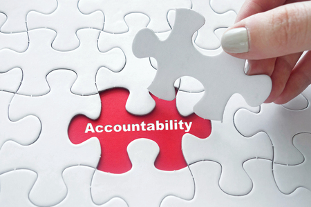 Close up of girl's hand placing the last jigsaw puzzle piece with word Accountabilityの写真素材