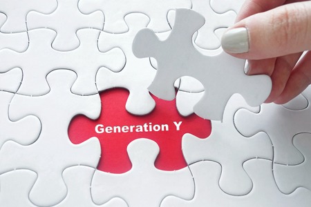 Close up of girl's hand placing the last jigsaw puzzle piece with word Generation Yの写真素材