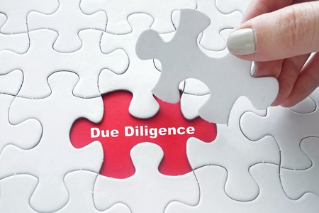 Close up of girl's hand placing the last jigsaw puzzle piece with word Due Diligenceの写真素材