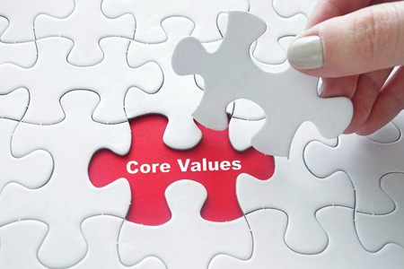 Close up of girl's hand placing the last jigsaw puzzle piece with word Core Values as business conceptの写真素材