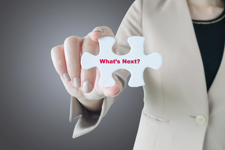 Businesswoman holding a piece of jigsaw puzzle: What's Next?の写真素材