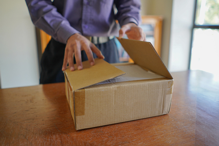 Selective focus of young man unboxing a parcelの写真素材