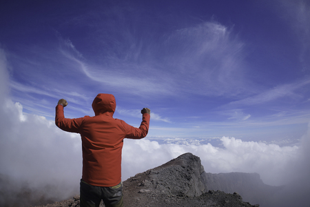 Victory concept: A man raising his hand at the peak of Mount Kerinchiの写真素材