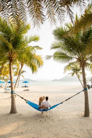 a couple loving hug each other while seating on a hammock at the beachの写真素材