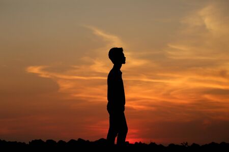 a silhouette of a boy during sunsetの写真素材