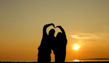 a silhouette of a loving couple making love sign using their bodyの写真素材
