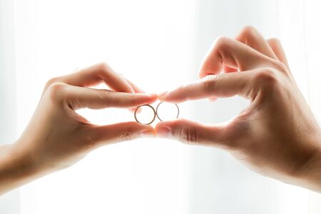 a loving couple holding their wedding ring closer to each otherの写真素材