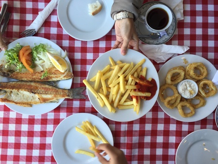 A shot of a person passing a plate of French fries over seafood meal. The shot was taken at Bosphorus, Istanbul Turkey.の素材