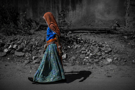 A selective color shot of a woman in traditional indian clothing walking down the street in Ajmer, India.の写真素材
