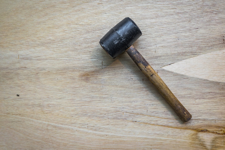 A shot of a rubber mallet over a wooden surface.
