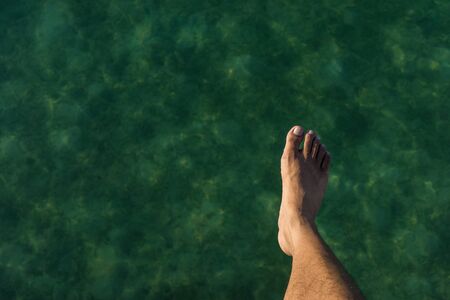 A shot of a person's foot in the air while jumping into the ocean.の写真素材