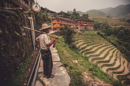 Guilin, China - June 15, 2014 : A worker or farmer looking at the view of his hard work. The shot was taken at Guilin, China where the locals here at Longji Paddy Terrace live a simple life by growing and farming their own food.のeditorial素材