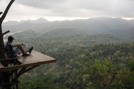 Kalibiru National Park, Jogjakarta Indonesia: August 19th 2017 - Shot of a person sitting on a wooden platform enjoying the vast view of Kalibiru National Park in Jogjakarta Indonesiaのeditorial素材
