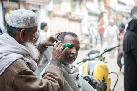 Old Delhi, India : February 15th, 2015 - A shot of a barber shaving out in the street of Old Delhi, India.のeditorial素材