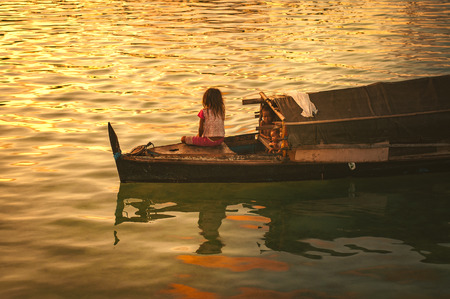 Denawan Island, Sabah Malaysia : April 30th, 2016 - Shot of a group of children watching the sunrise from their small wooden boathouse.のeditorial素材