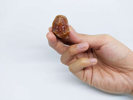 hand holding date fruit (kurma sukkari) isolated on white background