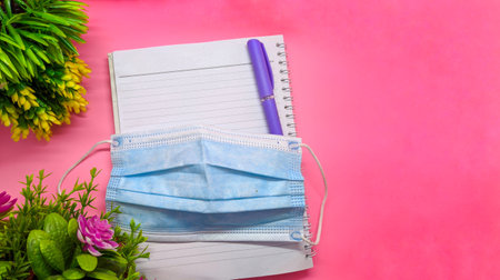 object with flowers decoration on soft pink background. with the theme of back to school during a pandemic. perfect for cover and banner concepts. copy space, flat lay, top view.の写真素材