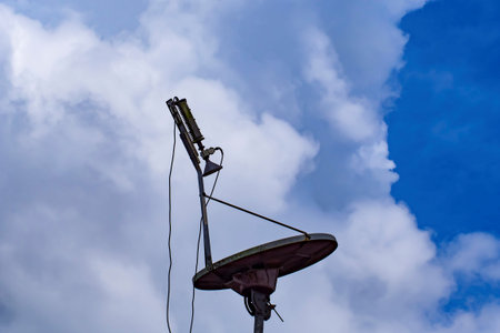 Stock photo of a satellite dish setup with feed horn and LNB, connected by cables. Represents...