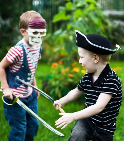 two brothers wearing pirate costumes and skull mask fightingの写真素材