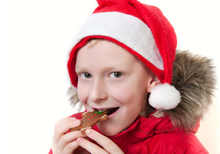 Young boy wearing santa hat eating gingerbread man の写真素材