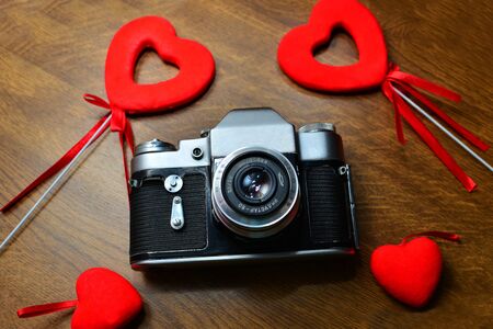 retro camera with red heart on wooden table. Vintage style