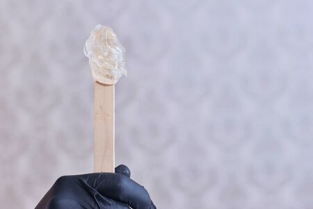 Woman with sugar paste or wax honey and black gloves handの写真素材