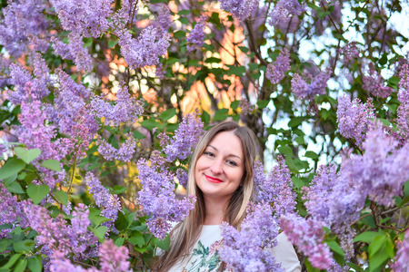 Woman with long blond hair in the garden with flowers. Beautiful girl on a sunny day.の写真素材