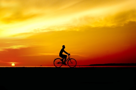 silhouette of the cyclist riding at sunsetの写真素材