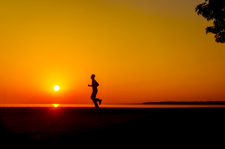 silhouette person jogging at great sunsetの写真素材