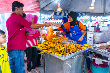 JOHOR, MALAYSIA-JUNE 29: Unidentified traditional roast chicken attends to a customer at Pasar Ramadhan Bukit Gambir on June 29, 2014 in Johor, Malaysia. Muslims around the world start fasting today.のeditorial素材