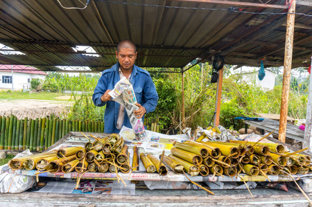 PAHANG, M'SIA-JULY 27: Unidentified Malaysian traditional food seller was packing "lemang" at Kuantan town on July 27, 2014 in Pahang, Malaysia. Muslims around the world celebrate Aidilfitri tomorrowのeditorial素材