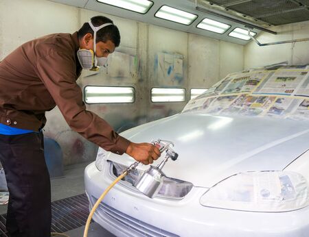 Worker painting a car in a paint boothの写真素材