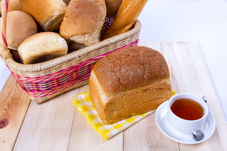 Wicker basket with brown bread and tea on a white background