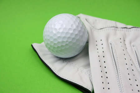 Golf glove and ball on a green backgroundの写真素材