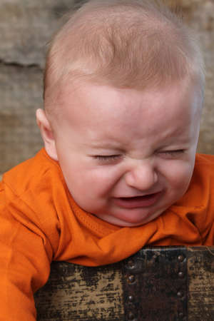 Three month old baby boy inside an antique trunk crying
