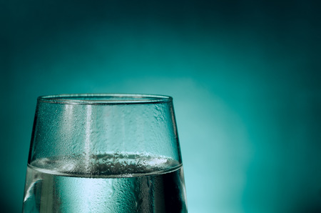 A glass of fresh water dripping with water isolated on an aqua background. Good composition for text addition, simple and clear.の写真素材
