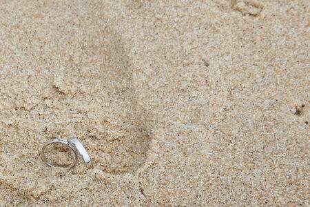 Footprints on beach with wedding ringsの写真素材