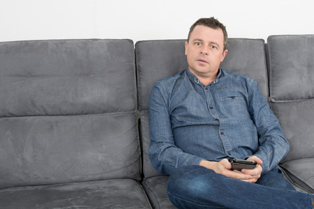 A man typing text message on his cellphone on his sofa