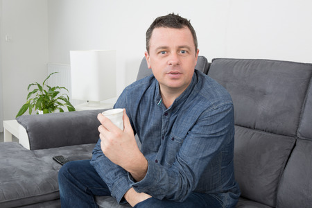 Attractive man having a coffee in a living roomの写真素材