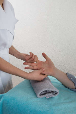 A man in a nail salon receiving a manicureand a massage  by a beauticianの写真素材
