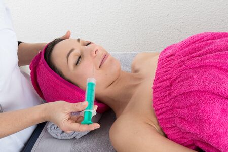 Young woman receiving a botox injection in her cheekの写真素材