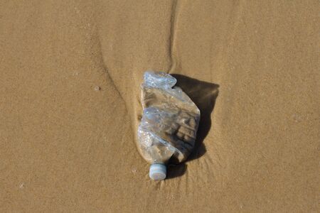 A blue plastic bottle littering a beach - pollutionの写真素材