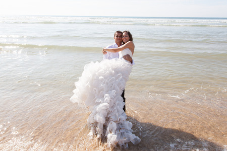 Happy couple just married relaxing on the beach laying in the oceanの写真素材