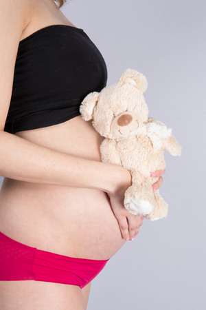 Woman expecting a baby with a cute teddy bearの写真素材