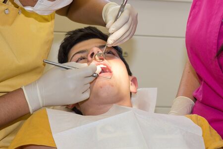 Woman dentist treats the boy's teeth with a drillの写真素材
