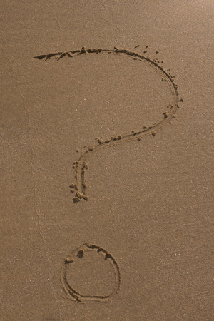 A question mark drawn on the sand of a beachの写真素材