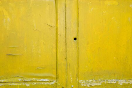 Background of yellow, peeling paint on an old wooden wallの写真素材