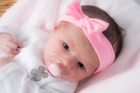 Newborn caucasian baby girl with pink bowの写真素材