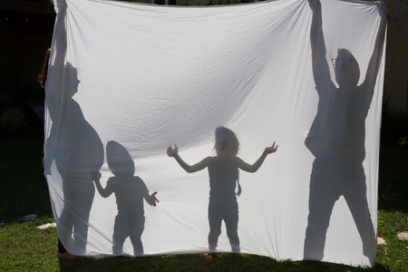 Shadows of a family behind a sheet -Symbol of a familyの写真素材